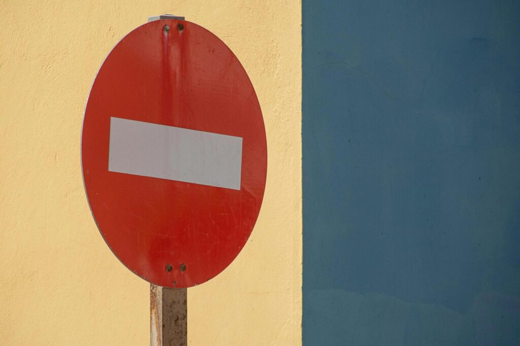 Ein rotes „Einfahrt verboten“-Schild vor einer leuchtend gelben und blauen Wand, ideal für urbane Themen.